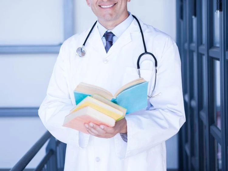 Uśmiechnięty lekarz trzymający książki